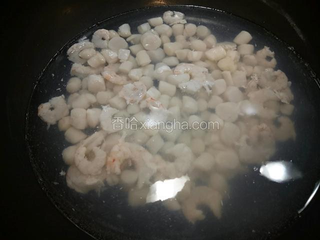 另取干净锅放足量水，加一勺料酒，烧至七八成开时，放入鲜虾仁和新鲜扇贝丁，焯水