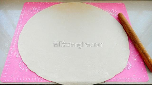 醒好的面团揉匀后擀成厚度约为0.3厘米的大圆片。（擀圆片时面垫上撒些面粉，圆片面皮上也要撒面粉防止粘连。）