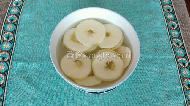 在一空碗中倒入适量水与盐，将削切好的苹果圈放入其中，避免氧化。