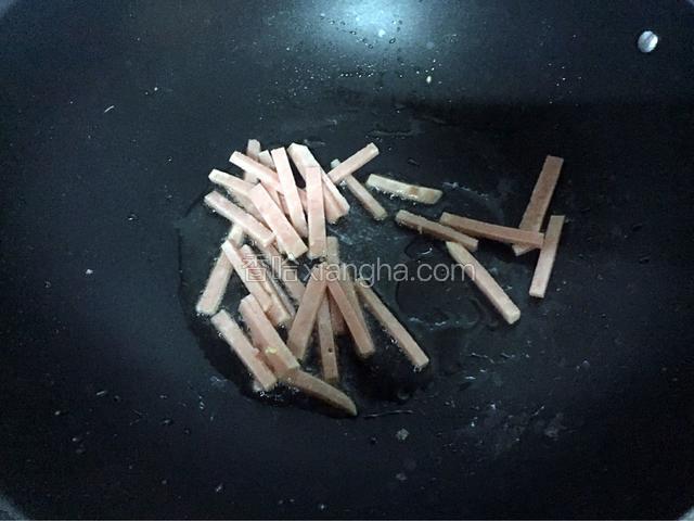 锅中再倒入少量油烧热后放入火腿翻炒至变色