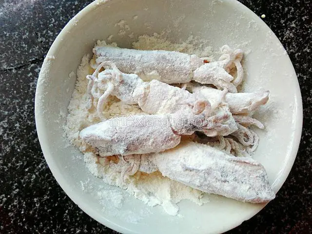 将清洗干净的鱿鱼仔均匀的裹上面粉。