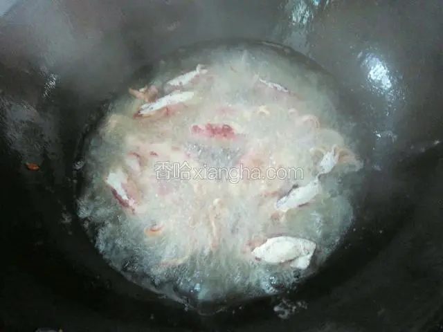 将裹上面粉的鱿鱼仔下入油锅油炸。