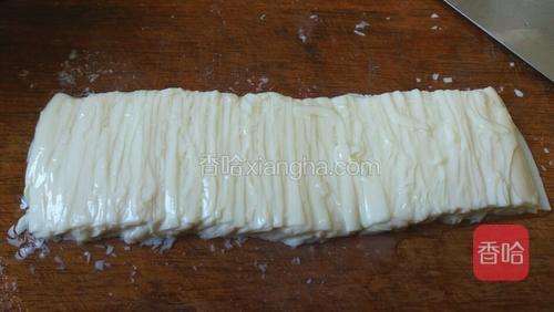尾部就不要了。刀沾水,用刀侧面将豆腐片捋平。