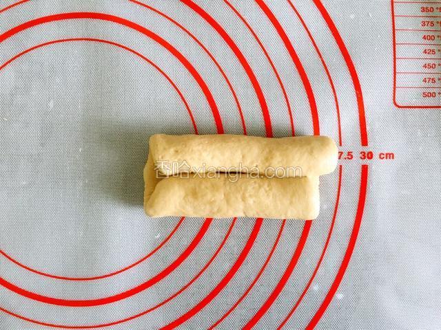 取一醒发好的面团擀成长椭圆形，自上下分别像中间卷。