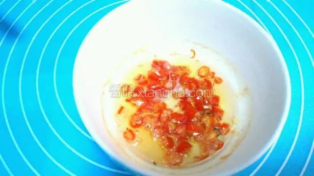 热油倒入装小米椒的碗里。辣椒油制成了。