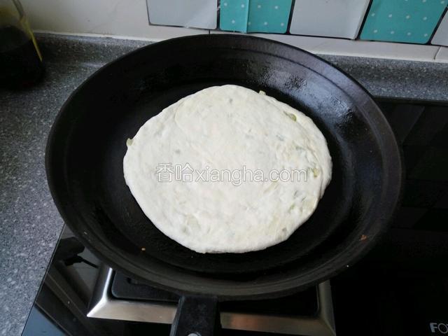 在用擀面杖擀开，放入提前预热饼铛，小火慢慢烙制