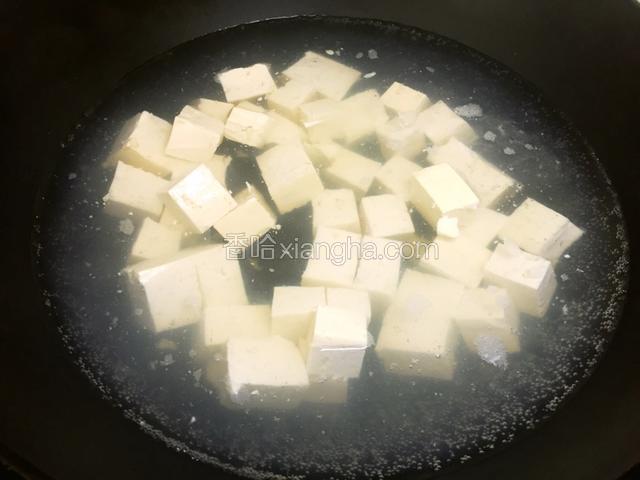 起锅烧水，煮豆腐，加盐适量，开锅后两分钟停火。将豆腐连水一起倒入容器里待用。
