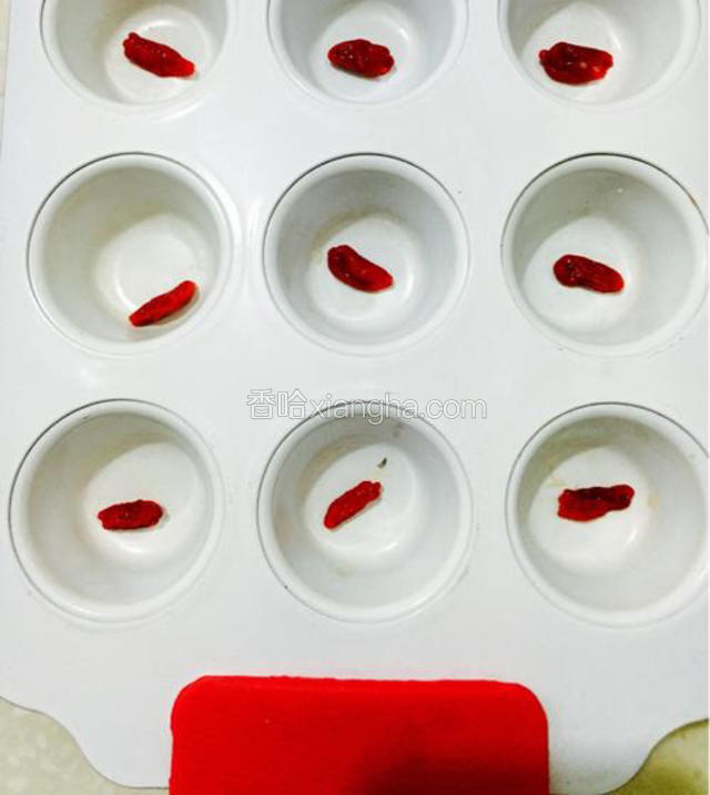 将泡好的枸杞擦干水分，摆入不粘马芬模中。