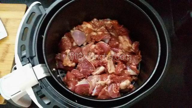把羊肉平铺在空气炸锅中。