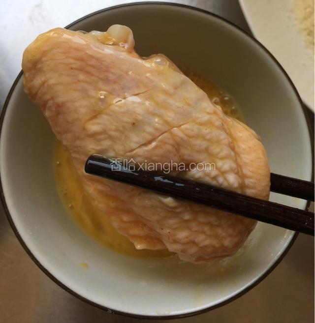 用筷子夹一个鸡翅中在蛋液里滚一下，控去多余蛋液；