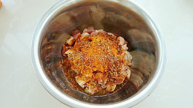 在羊肉块中放入玉米油和烧烤串料。