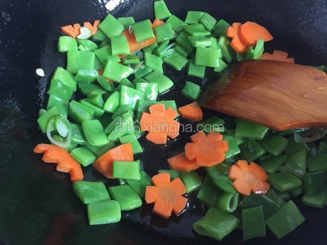 捞出豆角和胡萝卜倒入油锅煸炒1分半钟。