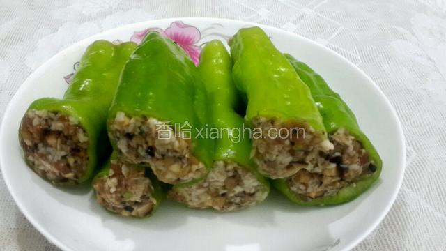 将拌好的肉馅塞进辣椒里,装好肉馅的辣椒放入蒸盘中。