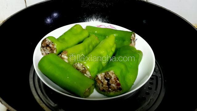 往蒸锅里添水，等水煮沸后，放入要蒸的辣椒，一定要隔水蒸。