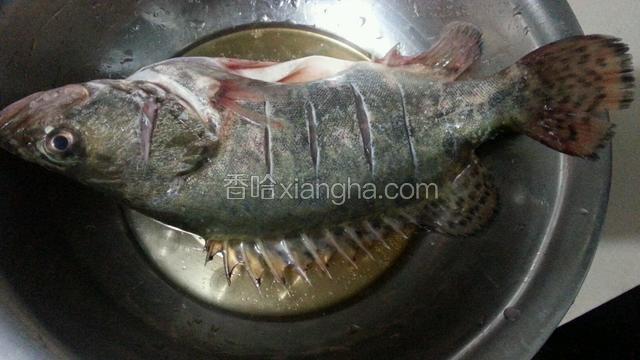 在鱼放在盆中，加入盐和料酒腌制20分钟