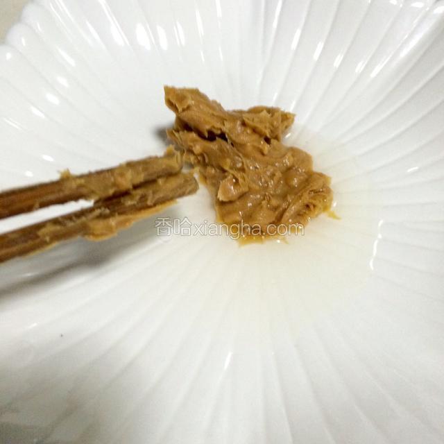 从花生酱罐内挑出适量的花生酱，加入盘子内。