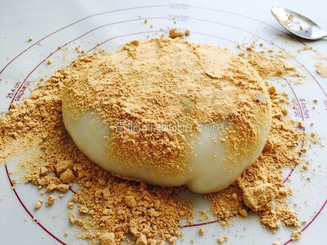 在面板上撒上一层熟豆面，放上糯米团，再在糯米团上撒上一层豆面。