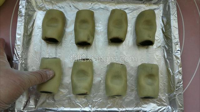放入烤盘留出间距，用姆指在每个豆沙卷上面轻压一下