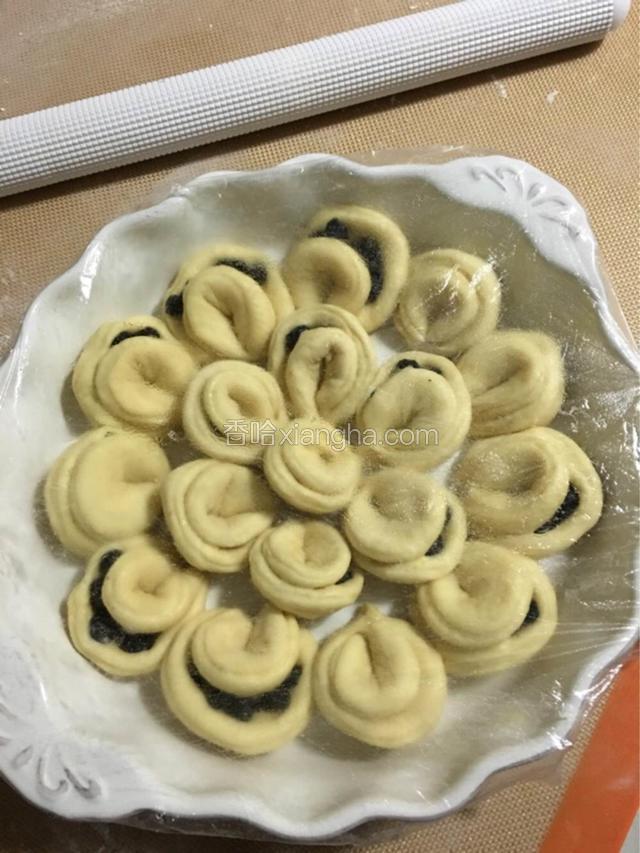 依次整好形，把这些大馄饨全部放入烤盘中，盖上保鲜膜，放入烤箱中发酵；