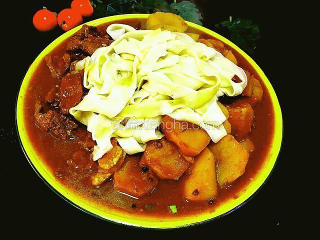 这时间鸡肉也煮熟了，可以盛盘上桌子了。然后将面铺在肉的上面，这就是正宗的新疆大盘鸡吃法，大盘鸡+皮带面绝配!