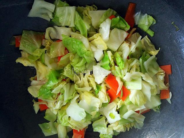 圆白菜和胡萝卜入锅翻炒，加少量清水煮至熟软。