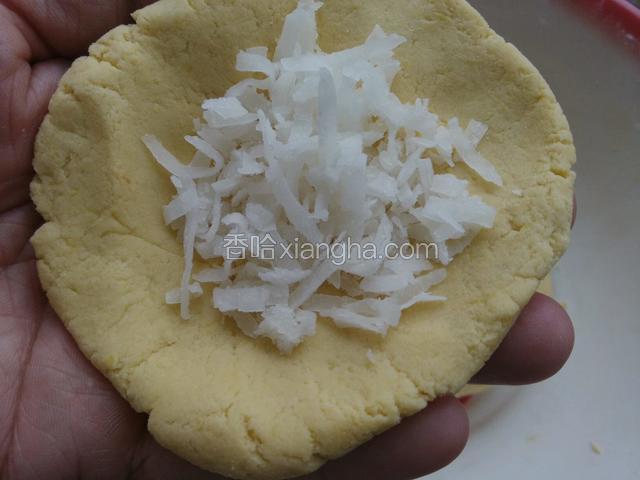 面团分几等份，用手按成饼，加甜椰丝，包包子状，并压成饼。