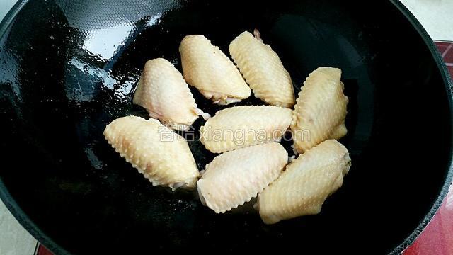 另起锅放适量油烧热后改小火，放入鸡翅煎制。