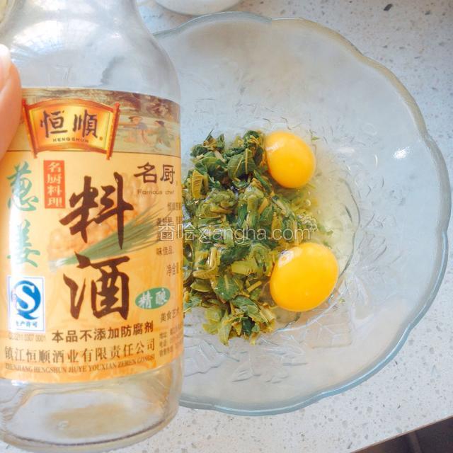 把切好的香椿放入碗中，打两个鸡蛋进去，在鸡蛋上滴少许料酒去腥