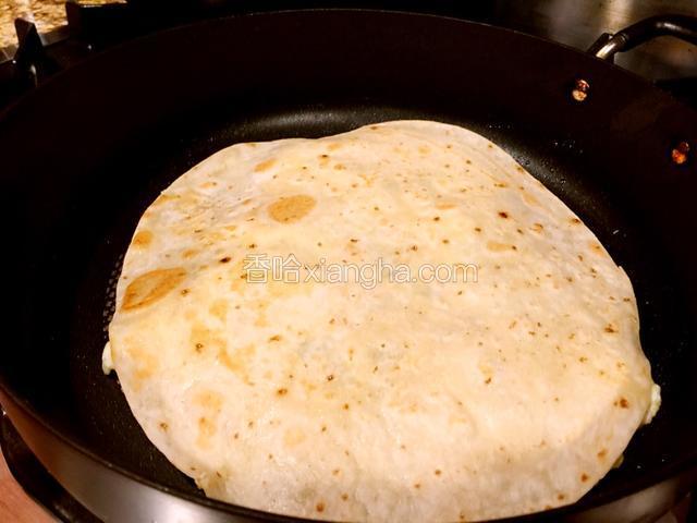 将现成的大饼盖在鸡蛋上面，用平底勺稍微按一下