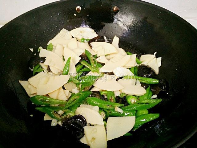 锅里放油，加入蒜粒爆香后，倒进笋片、木耳、尖椒翻炒均匀。