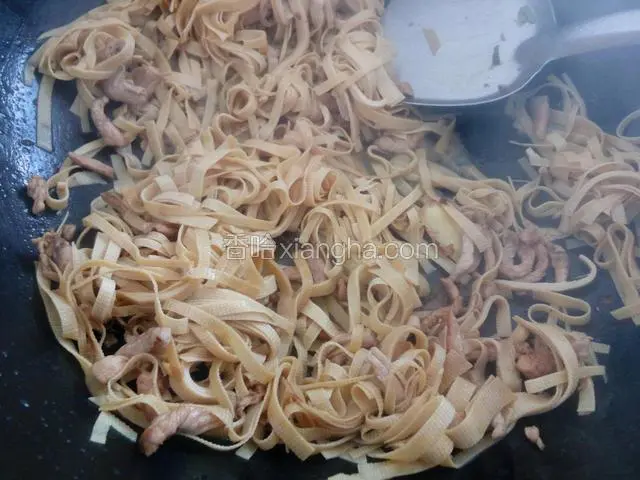 加入少许清水，倒入豆腐皮丝，继续翻炒
