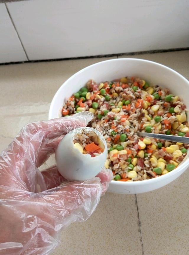 用小勺子把拌好的糯米食材灌进蛋壳中，直至八分满，最好压实，这样蒸出来的蛋外形美观，不易松散