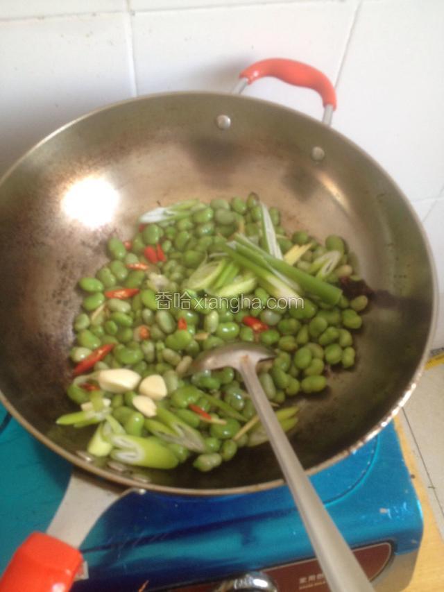 翻炒至兰花豆变色放入葱姜蒜小红椒进行翻炒可以适量放点白酒增加点香味去掉兰花豆的生的清气