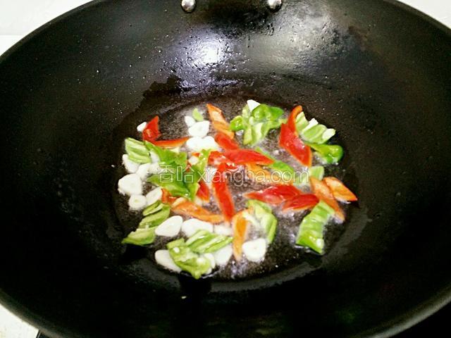 锅里放适量油烧热，加入青椒、红椒、蒜片炒出香味。