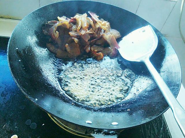 腊肉的油煸出大部分后，把腊肉推到锅的一端。放入姜蒜爆香。