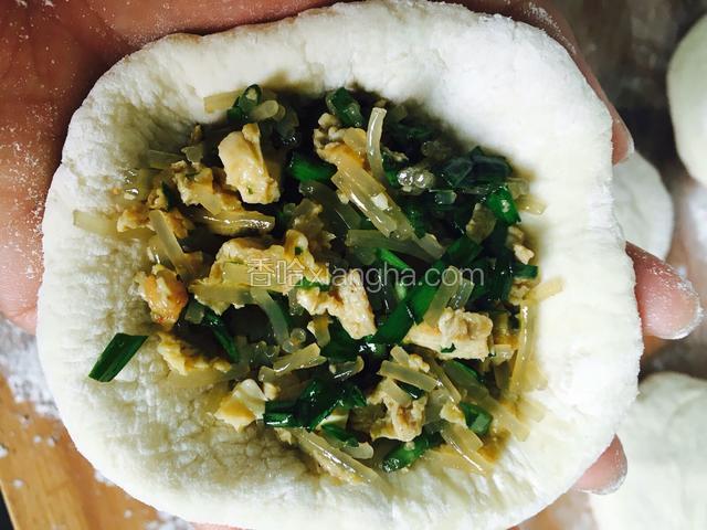 用擀面杖 擀成大圆形 就像擀饺皮一样 但不需要那么薄  放在手中。加入调好的韭菜粉丝馅 用手捏住开口