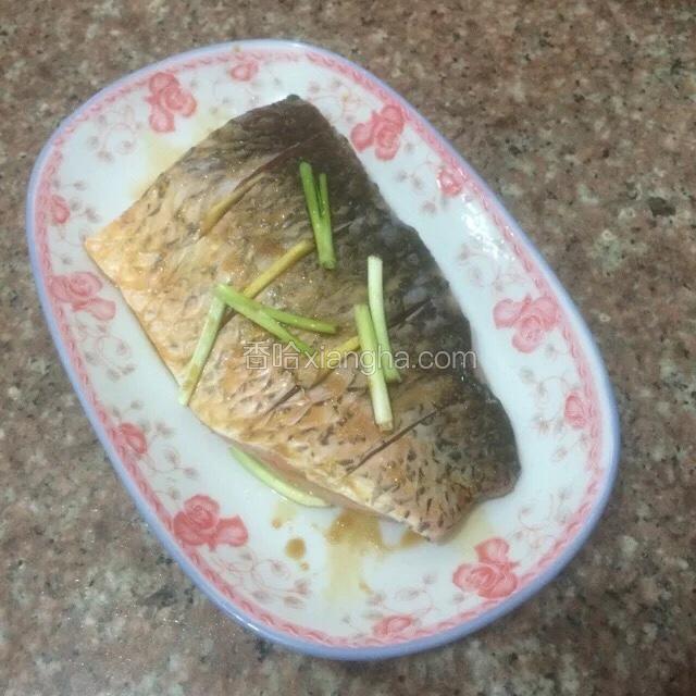 将鱼入盘后再在鱼身上撒些葱姜。