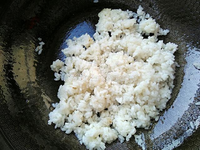油温七成热，加白米饭炒香。用铲子拍松散，使米饭均匀裹上油花。