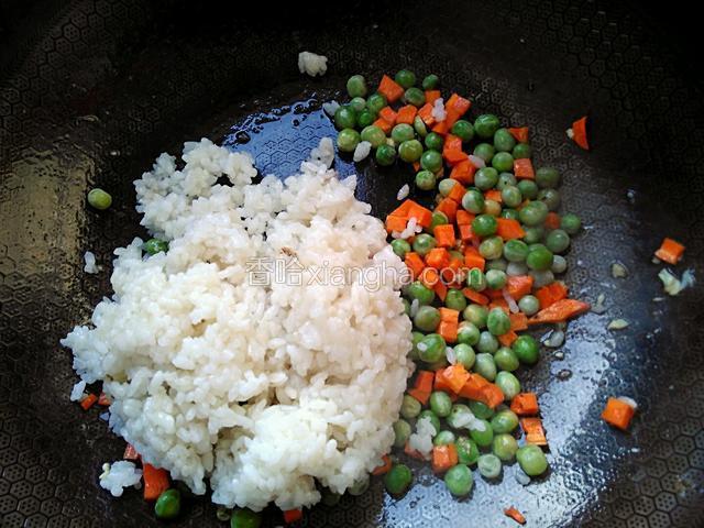 炒至豌豆粒和胡萝卜丁爆香，加入刚才盛出的米饭。