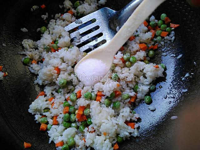 加一勺食盐，一勺白糖，一勺料酒，不断翻炒米饭和食材。