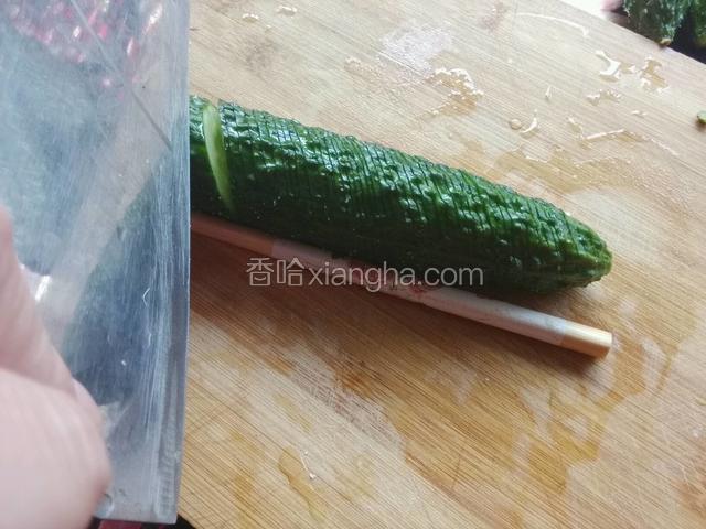 切黄瓜/黄瓜两侧放筷子，刀与黄瓜呈45度角切片，刀落筷子上不切断黄瓜。这面切完翻另一面直切，同样不切断。