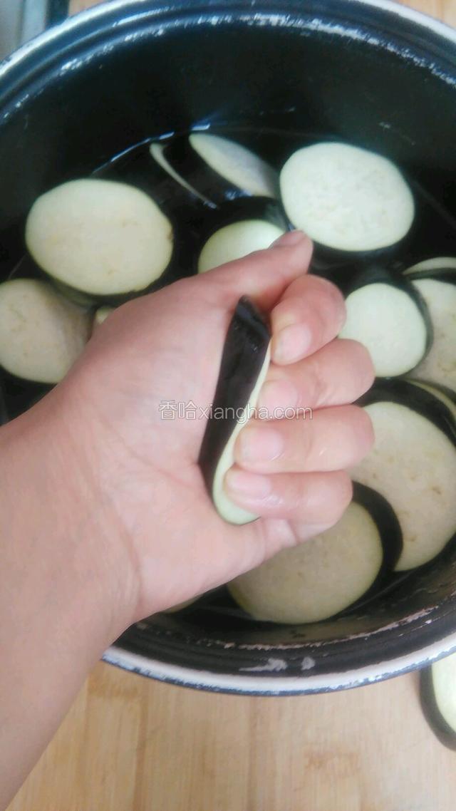 用手挤压茄子片，挤出水分。