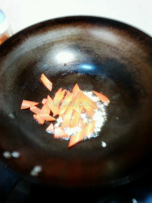八成热加入葱蒜炒出香味，加入胡萝卜炒两分钟