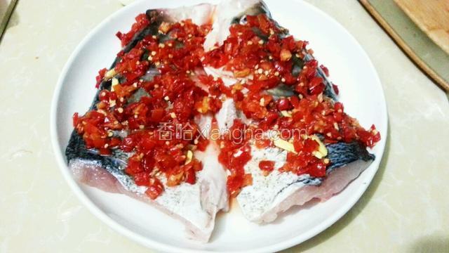 然后放入鱼头，加入盐，料酒，姜片，铺上剁椒