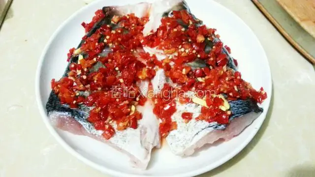 然后放入鱼头，加入盐，料酒，姜片，铺上剁椒