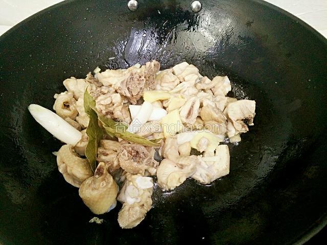 锅里放油烧热，倒入鸡块炒干水份，放入蒜粒、姜片、大葱结、香叶炒出香味。