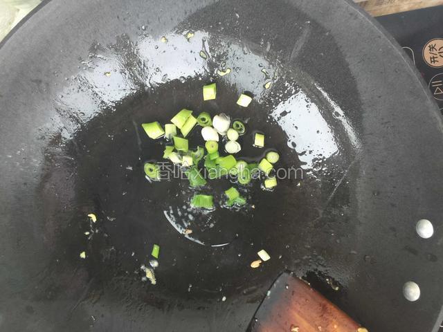 在锅中倒入花生油，加热后倒入切好的小葱，炝锅煸出香味。