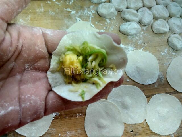 在饺子皮里放馅捏紧口。