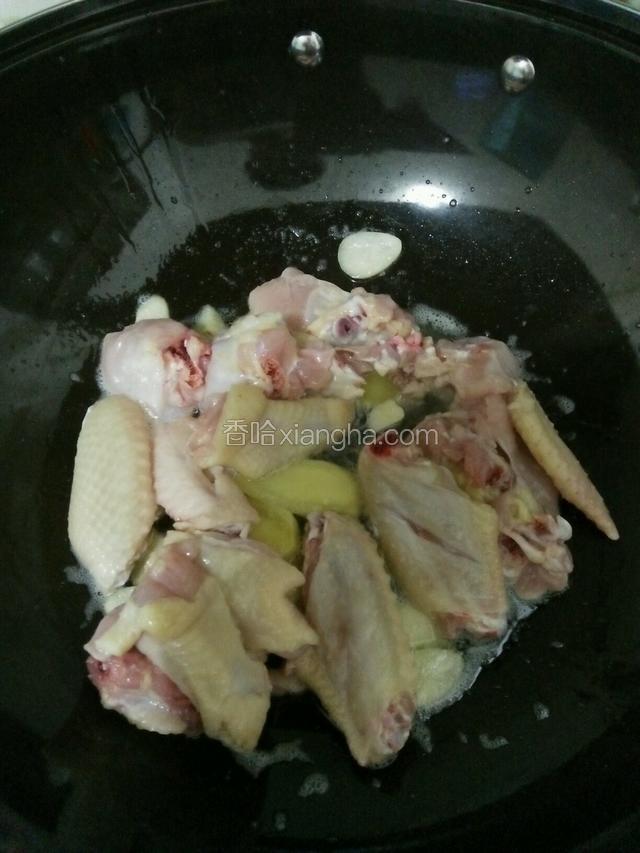 热锅下油接着下姜蒜爆香，然后下鸡翅、料酒翻炒