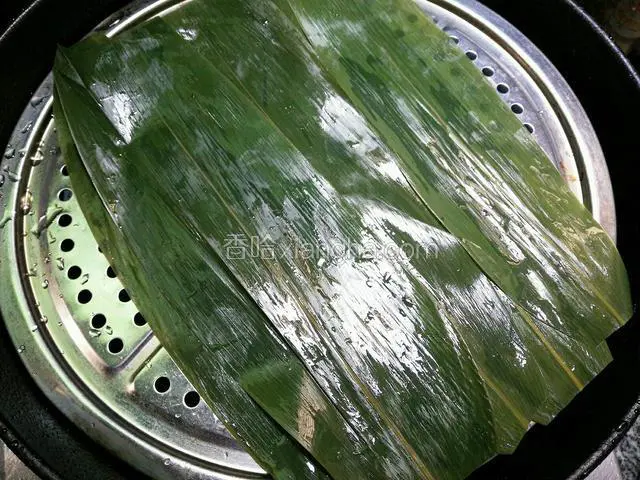 锅里加水，放上蒸屉，洗好的棕叶剪去两头平铺上